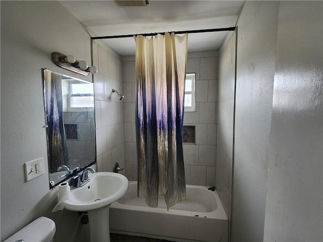 bathroom with shower / bath combination with curtain and toilet