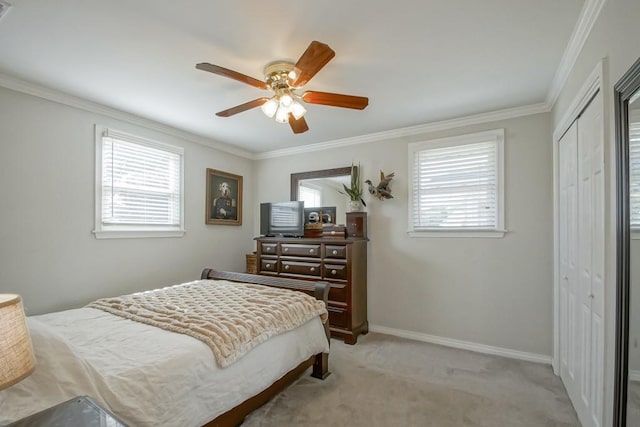 bedroom featuring baseboards, a ceiling fan, light colored carpet, crown molding, and a closet