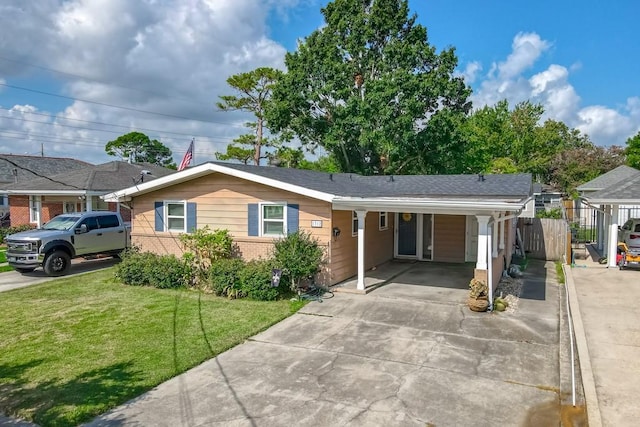 ranch-style home with brick siding, concrete driveway, a front yard, fence, and an attached carport