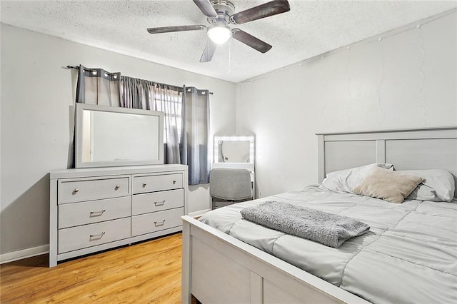 bedroom featuring ceiling fan, hardwood / wood-style floors, and a textured ceiling