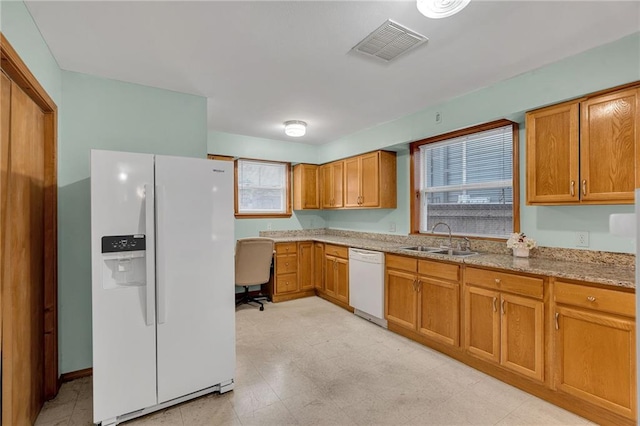 kitchen with white appliances, light stone countertops, and sink