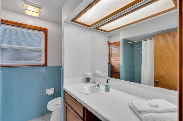 bathroom featuring walk in shower, vanity, toilet, and tile walls