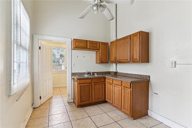 kitchen with sink, light tile patterned floors, ceiling fan, and a high ceiling