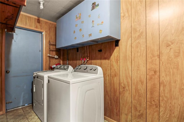 laundry room with cabinets, washer and dryer, and wood walls