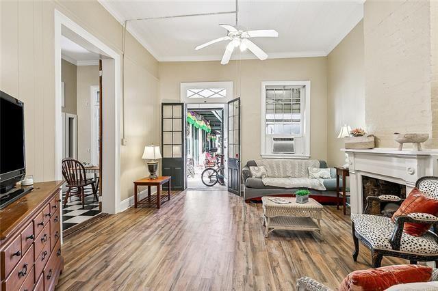 1224 Bourbon St Unit 1, New Orleans, LA 70116 - living area featuring a fireplace, ornamental molding, wood finished floors, a ceiling fan, and cooling unit