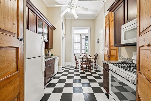 1224 Bourbon St Unit 1, New Orleans, LA 70116 - kitchen with white appliances, a ceiling fan, dark flooring, baseboards, and ornamental molding