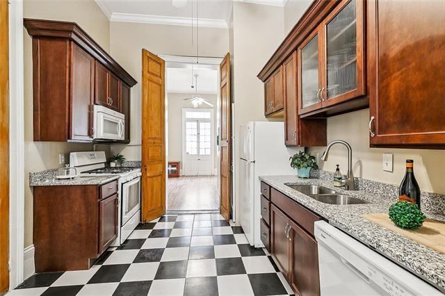1224 Bourbon St Unit 1, New Orleans, LA 70116 - kitchen featuring white appliances, crown molding, a sink, dark floors, and glass insert cabinets