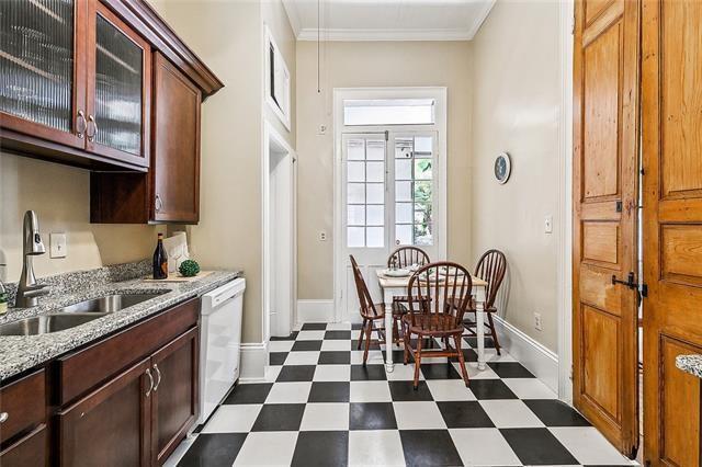 1224 Bourbon St Unit 1, New Orleans, LA 70116 - kitchen featuring a sink, dark flooring, dishwasher, baseboards, and glass insert cabinets