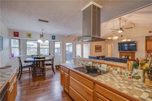 kitchen with island range hood, tile counters, black appliances, and dark hardwood / wood-style floors