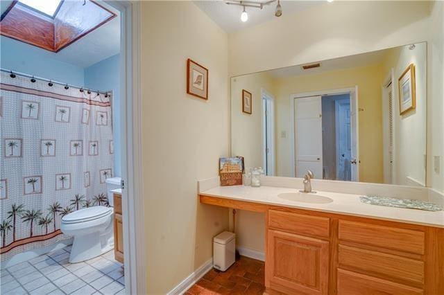 bathroom featuring vanity, toilet, a skylight, and a shower with shower curtain