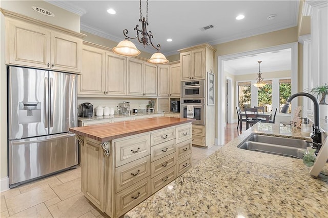 kitchen with stainless steel appliances, sink, wooden counters, and decorative light fixtures