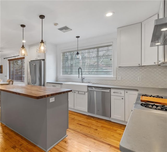 kitchen featuring appliances with stainless steel finishes, a center island, wooden counters, and white cabinets