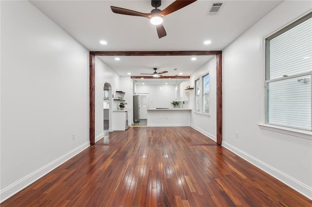 unfurnished living room with ceiling fan, dark hardwood / wood-style flooring, and beam ceiling