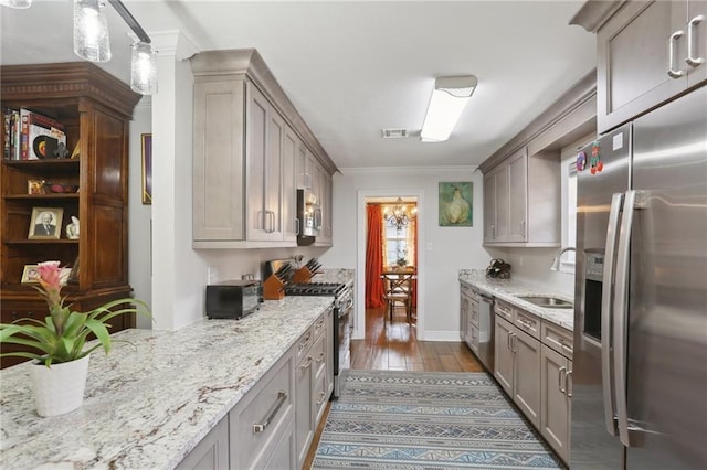 kitchen featuring sink, dark hardwood / wood-style flooring, hanging light fixtures, light stone counters, and stainless steel appliances