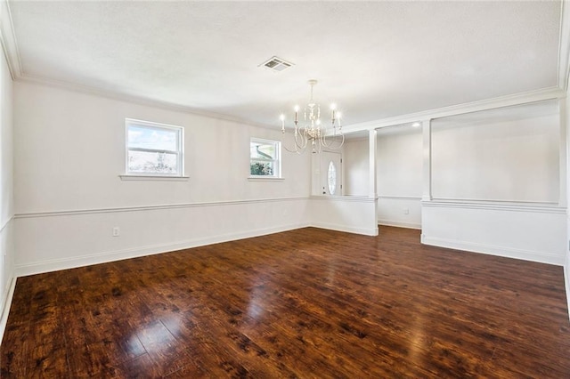 empty room featuring crown molding, dark wood-type flooring, and an inviting chandelier