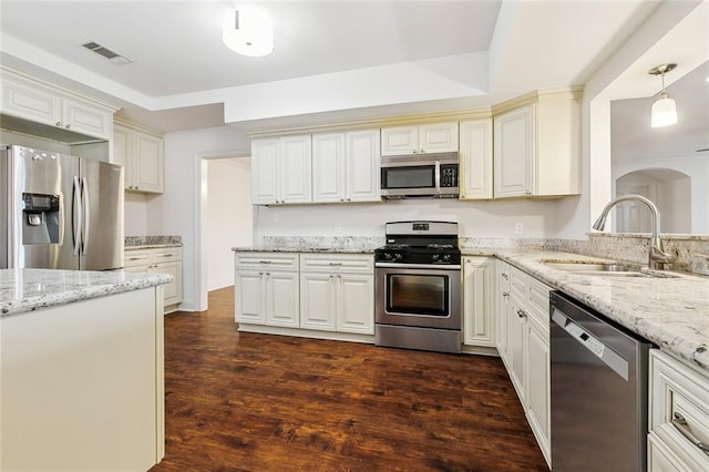 kitchen with pendant lighting, sink, light stone counters, and appliances with stainless steel finishes