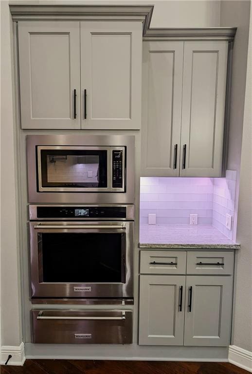 kitchen with appliances with stainless steel finishes, backsplash, and light stone counters