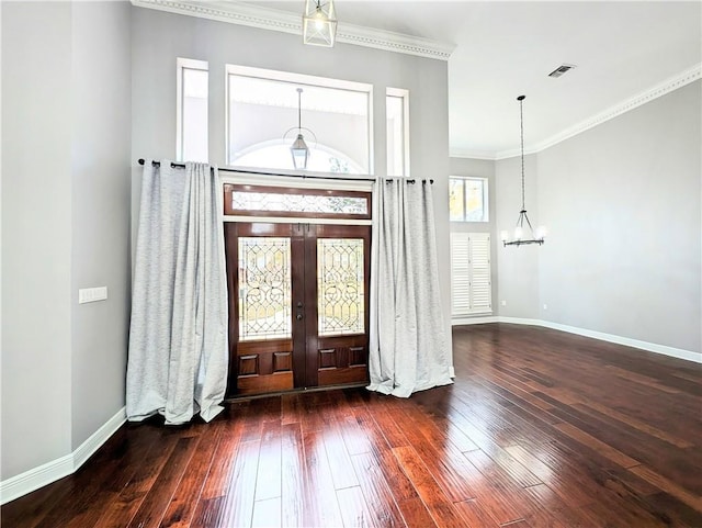 entrance foyer with an inviting chandelier, dark wood-type flooring, ornamental molding, and french doors