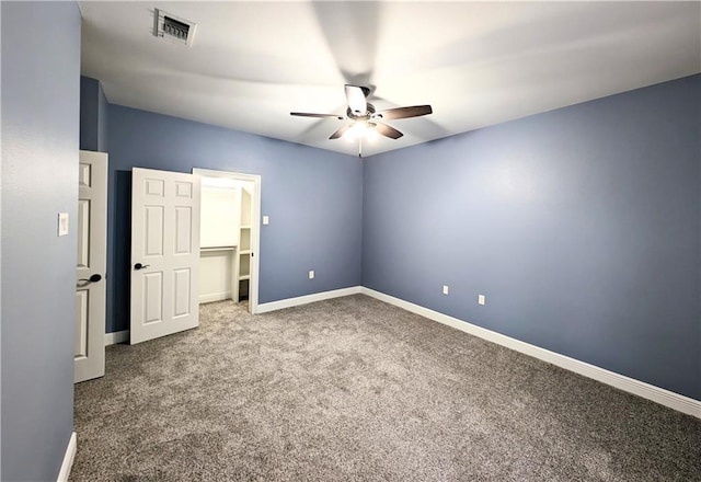 unfurnished bedroom featuring a spacious closet, a closet, ceiling fan, and carpet