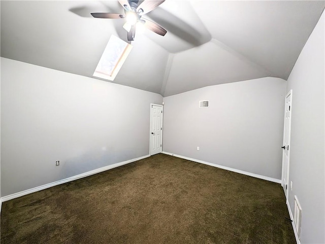 additional living space featuring dark colored carpet, vaulted ceiling with skylight, and ceiling fan