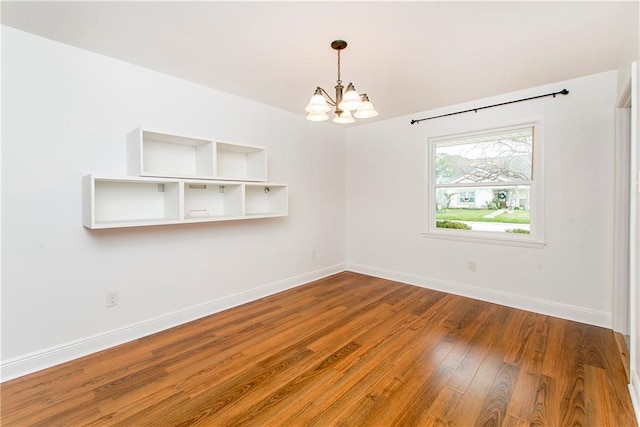 empty room with hardwood / wood-style floors and an inviting chandelier