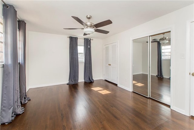 unfurnished bedroom with two closets, dark wood-type flooring, and ceiling fan