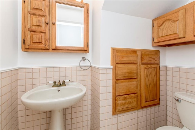 bathroom with toilet and tile walls