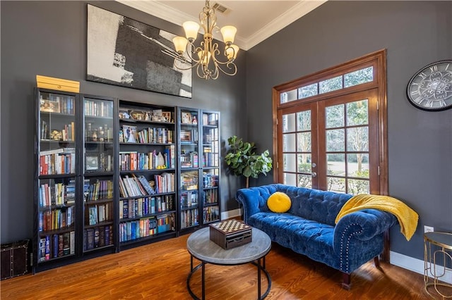 living area with hardwood / wood-style flooring, crown molding, an inviting chandelier, and french doors