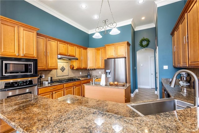 kitchen featuring pendant lighting, sink, appliances with stainless steel finishes, a center island, and light stone countertops