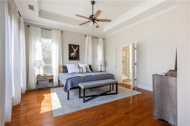 bedroom featuring hardwood / wood-style flooring, ornamental molding, and a tray ceiling