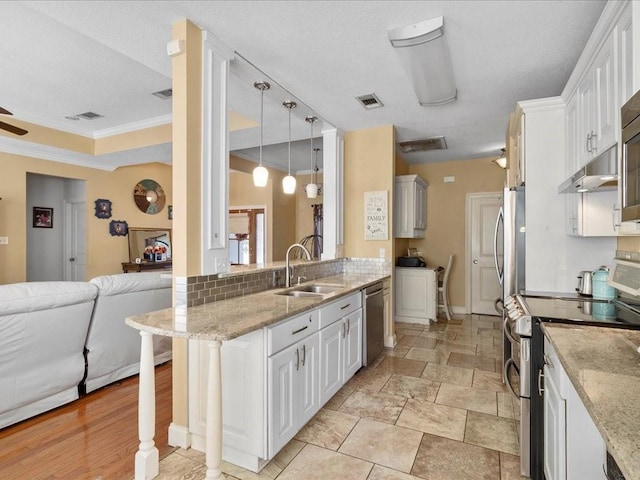 kitchen with appliances with stainless steel finishes, pendant lighting, sink, white cabinets, and a kitchen bar