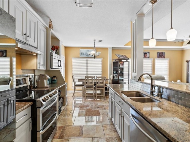 kitchen with gray cabinets, sink, dark stone counters, hanging light fixtures, and stainless steel appliances