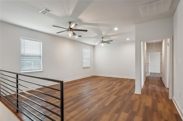 empty room with visible vents, attic access, baseboards, and wood finished floors