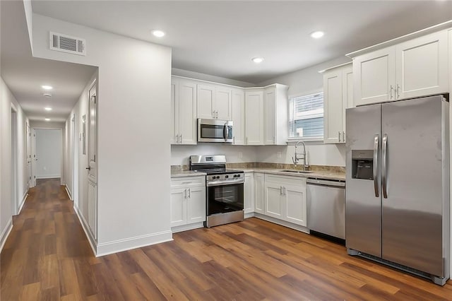 kitchen with visible vents, a sink, white cabinetry, stainless steel appliances, and dark wood-style flooring