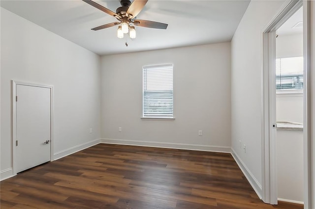 empty room featuring dark wood finished floors, baseboards, and ceiling fan