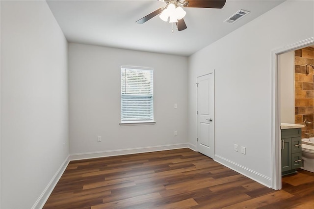 unfurnished bedroom featuring visible vents, ensuite bathroom, baseboards, and dark wood-style flooring