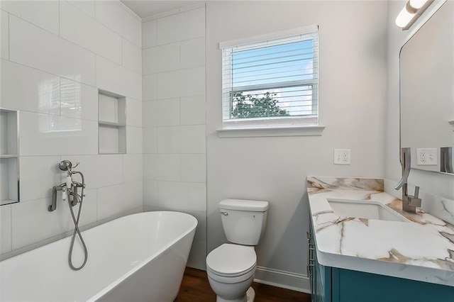 full bath with vanity, a soaking tub, toilet, and baseboards