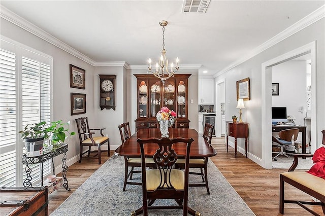 dining space with ornamental molding, a chandelier, and light wood-type flooring