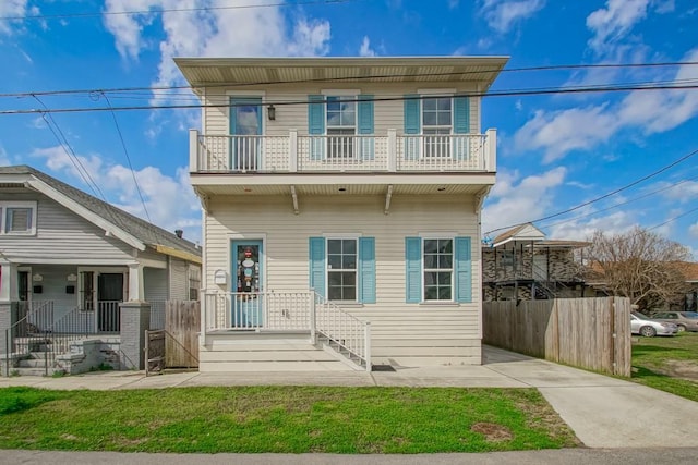 view of front facade featuring a balcony and a front yard