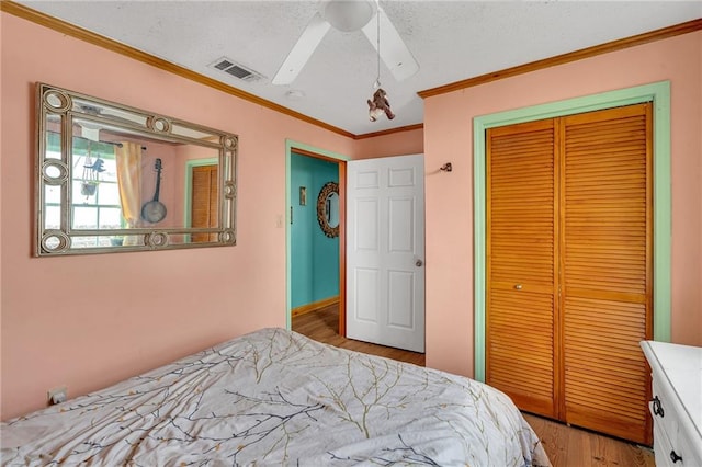 bedroom with ornamental molding, ceiling fan, light hardwood / wood-style floors, a textured ceiling, and a closet