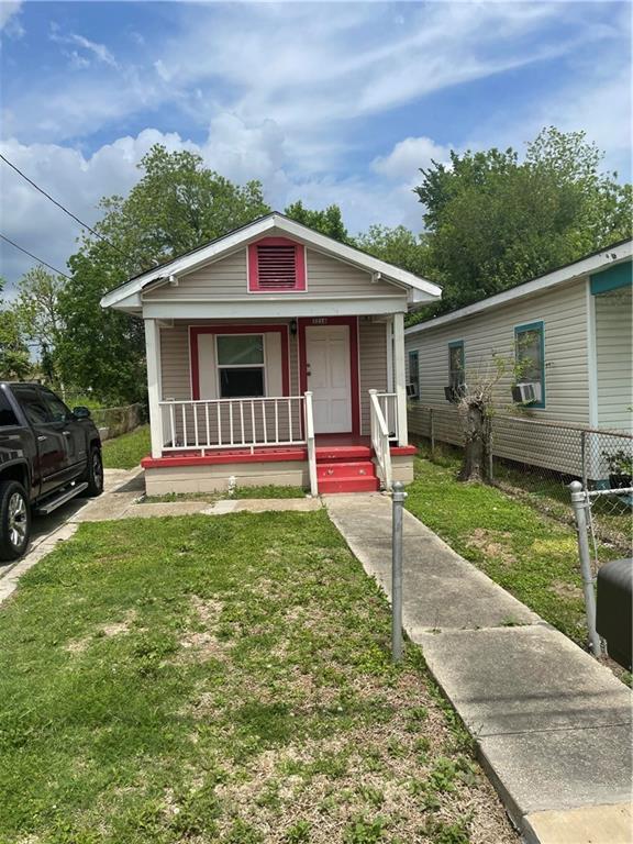 bungalow-style house featuring cooling unit, covered porch, and a front lawn