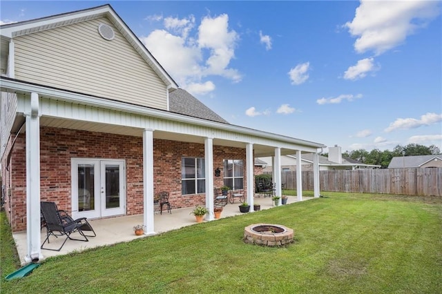 rear view of property featuring french doors, a patio, a fire pit, and a lawn