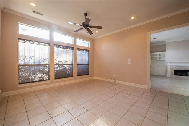 tiled spare room with ornamental molding, ceiling fan, a fireplace, and built in shelves