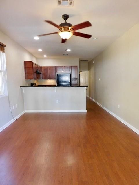 kitchen featuring fridge, dark wood-type flooring, ceiling fan, and kitchen peninsula