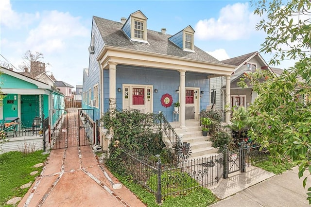 view of front of home with a gate, covered porch, a fenced front yard, and roof with shingles