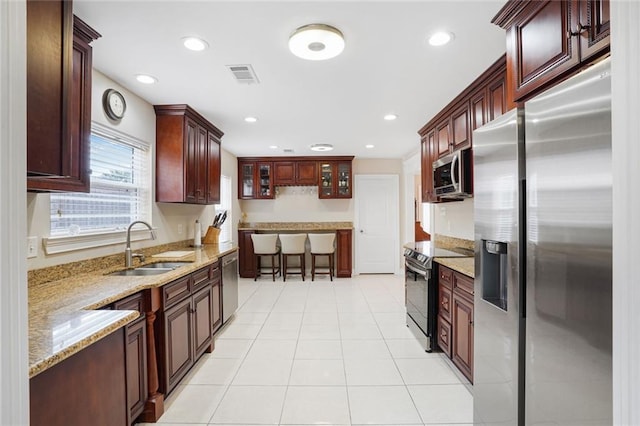 kitchen featuring sink, stainless steel appliances, light stone countertops, and light tile patterned flooring