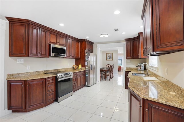 kitchen featuring stainless steel appliances, light stone countertops, sink, and light tile patterned floors