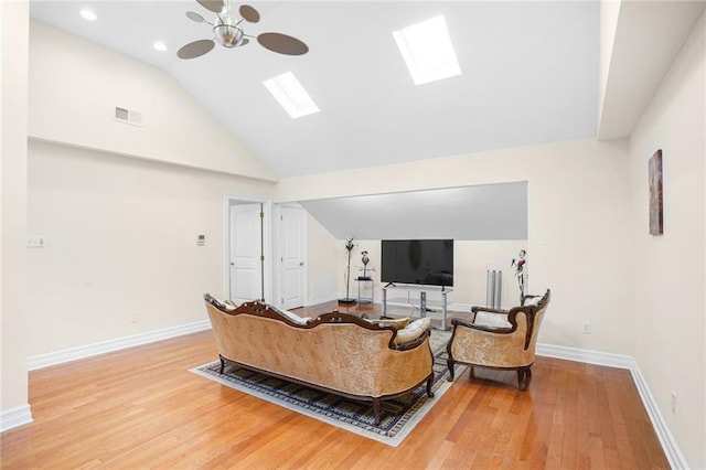 living room with hardwood / wood-style flooring, a skylight, and high vaulted ceiling