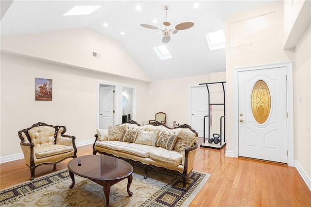 living room with a skylight, high vaulted ceiling, and light wood-type flooring