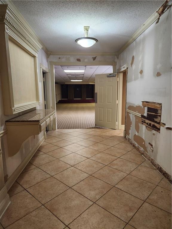 hallway featuring crown molding, light tile patterned floors, and a textured ceiling